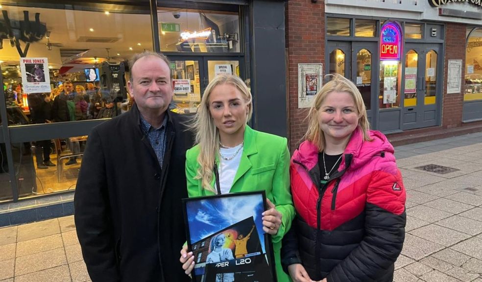 Alex Greenwood (centre) being presented with a framed copy of her mural by Sefton Council Cabinet Members Cllr Ian Moncur (left) and Cllr Trish Hardy (right).