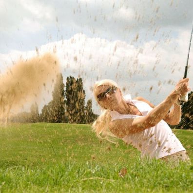 Golfer plays bunker shot